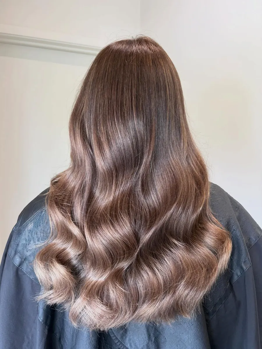 Mid-length brunette hair with soft rose-brown tones, styled in loose waves